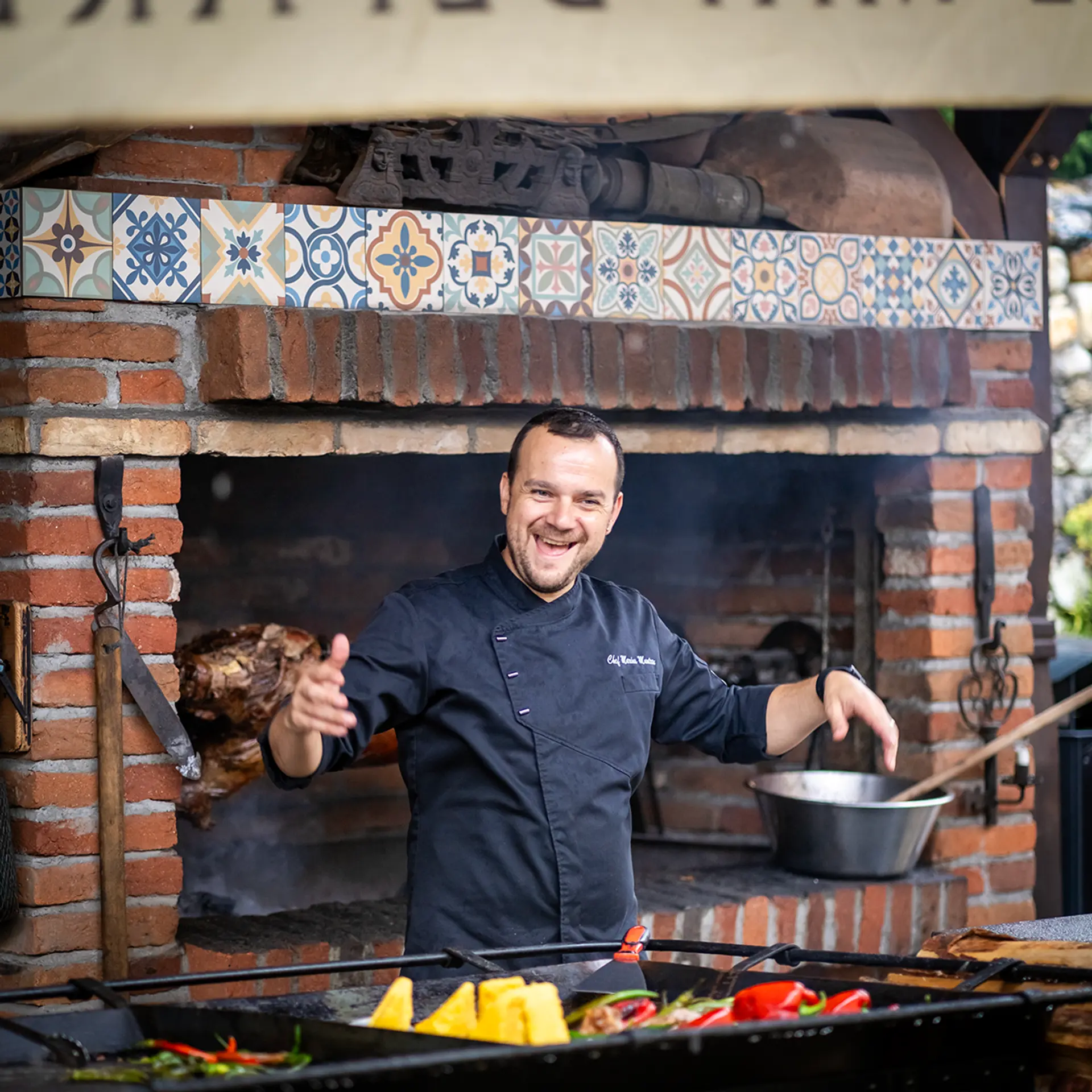 Koch lacht am Grill vor einer gefliesten Wand