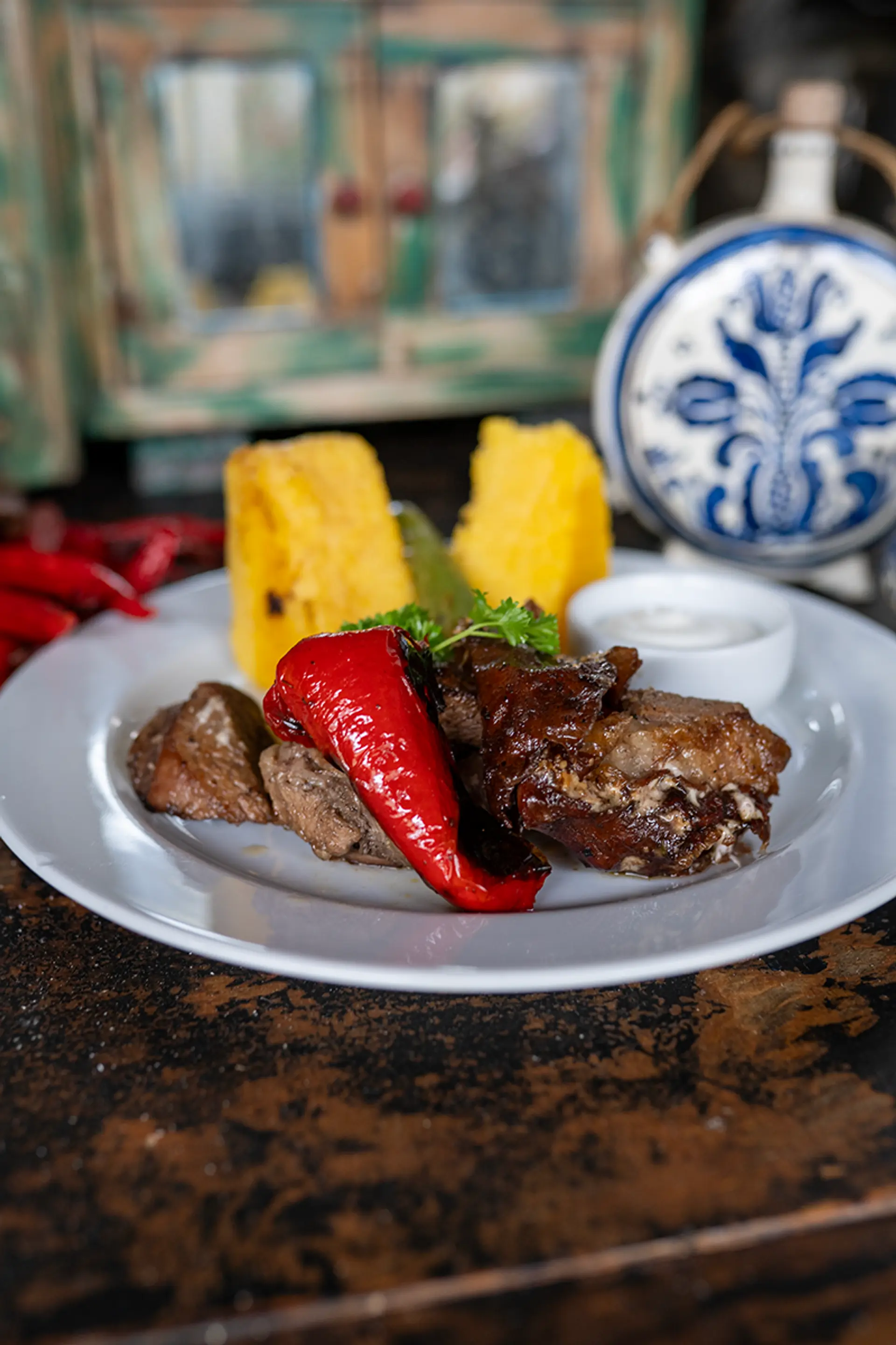 Gegrilltes Fleisch mit roter Paprika und Mămăligă, rustikal angerichtet