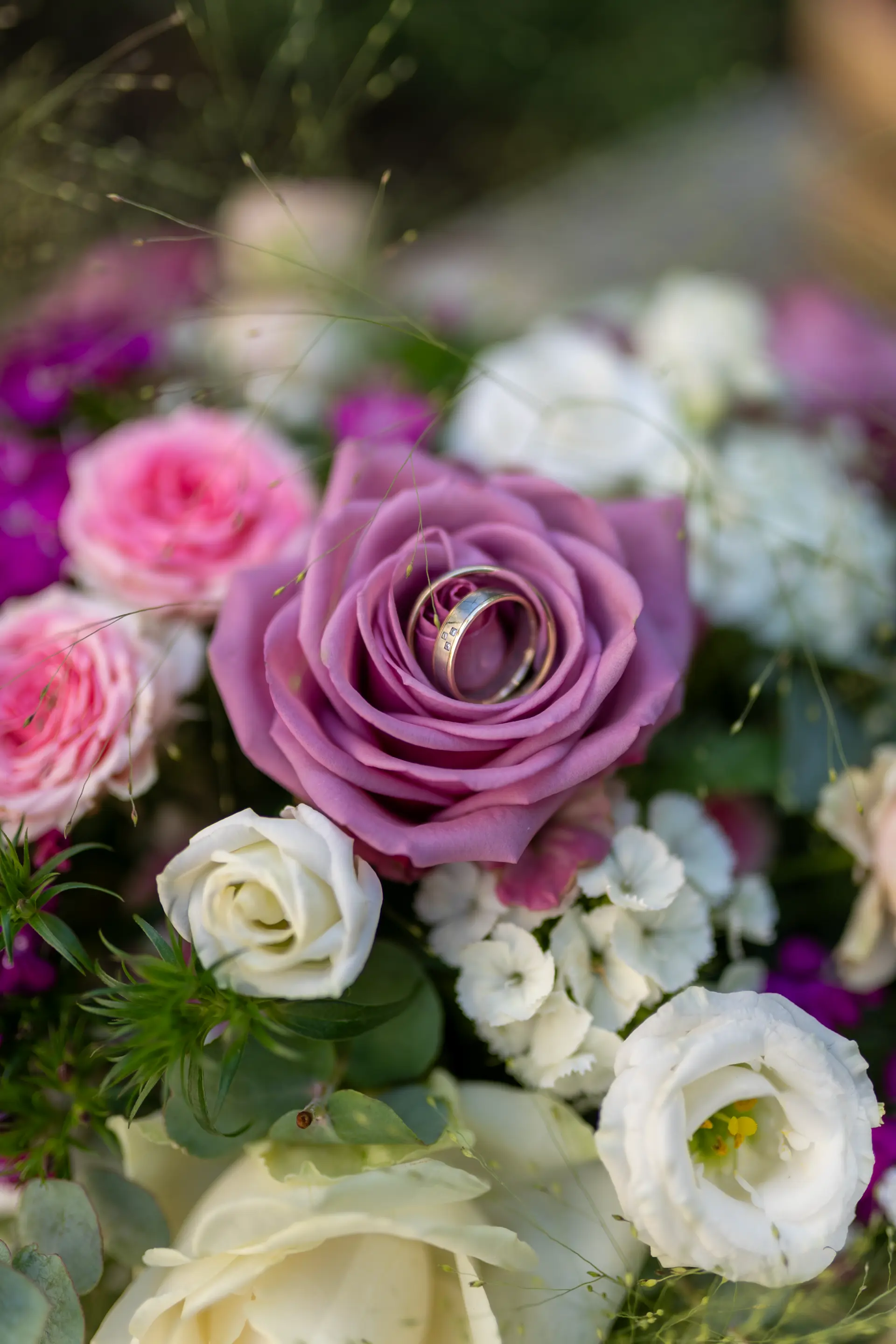 Eheringe auf einer lila Rose im Brautstrauß, Makroaufnahme