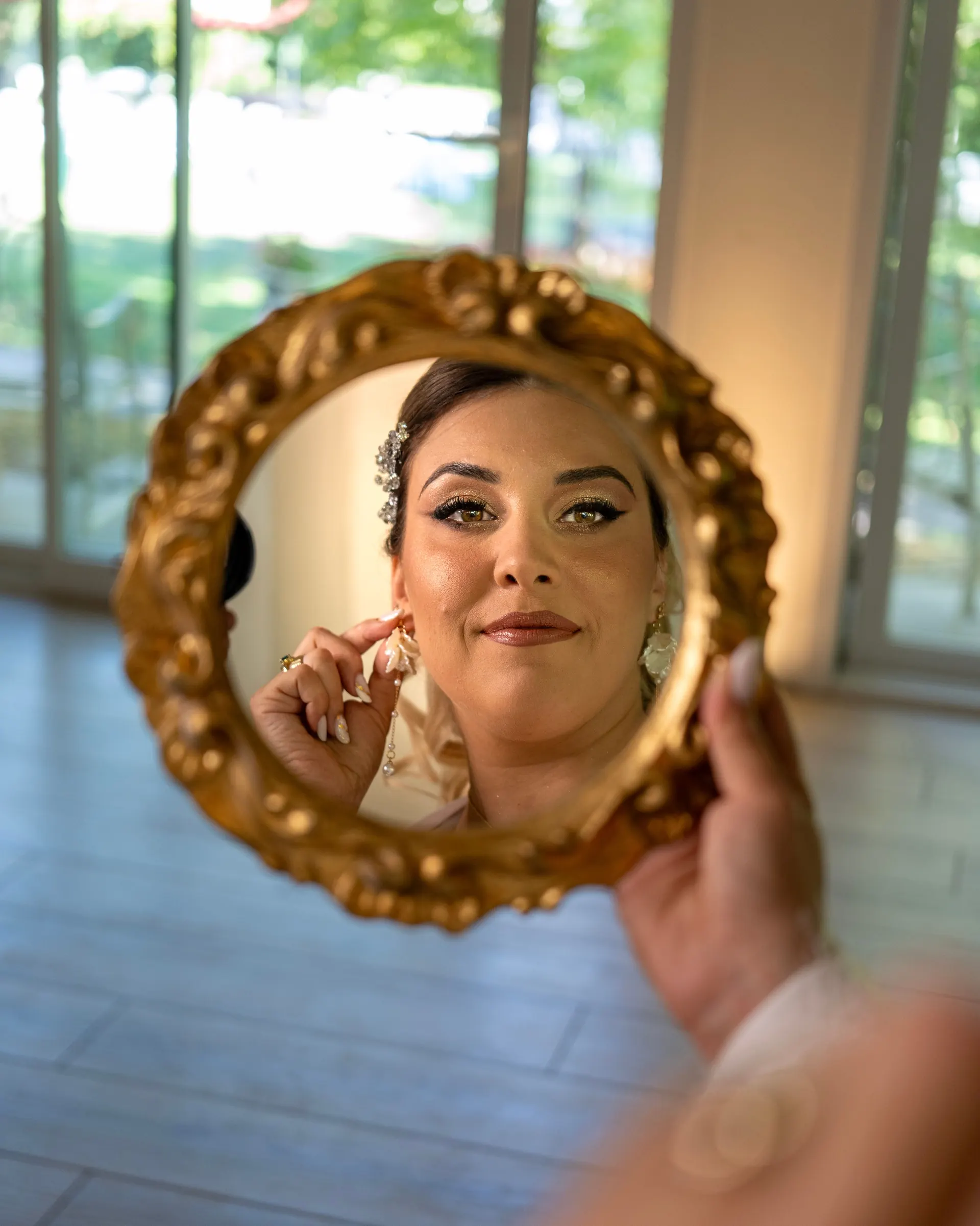 Braut spiegelt sich beim Getting Ready in einem goldenen Handspiegel