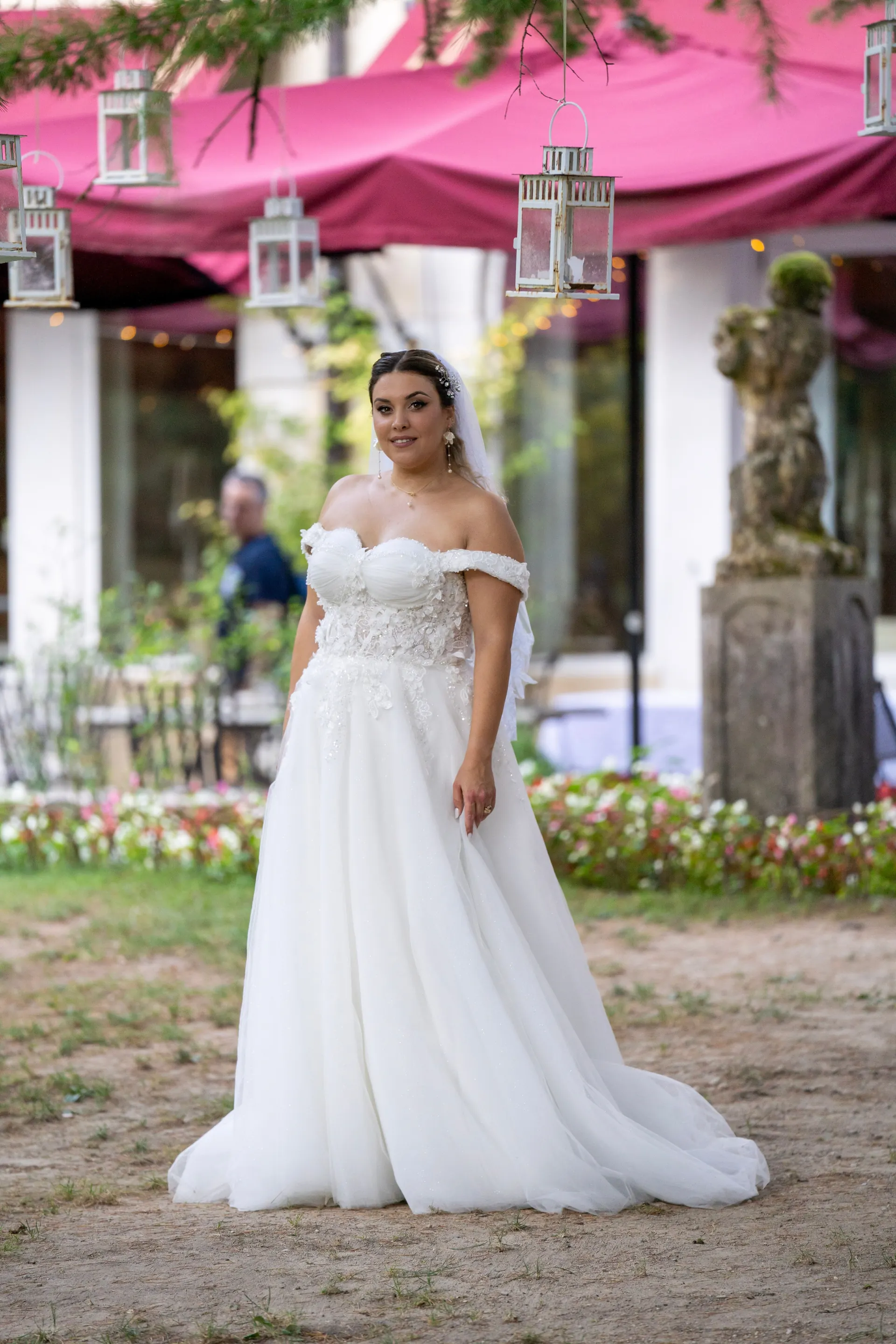 Braut im schulterfreien Kleid vor der Terrasse mit pinkfarbenen Markisen