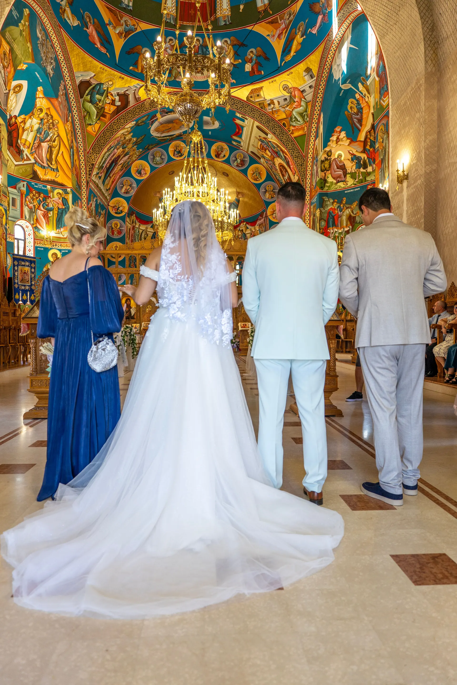 Brautpaar vor dem Altar einer Kirche mit farbenprächtigen Wandmalereien