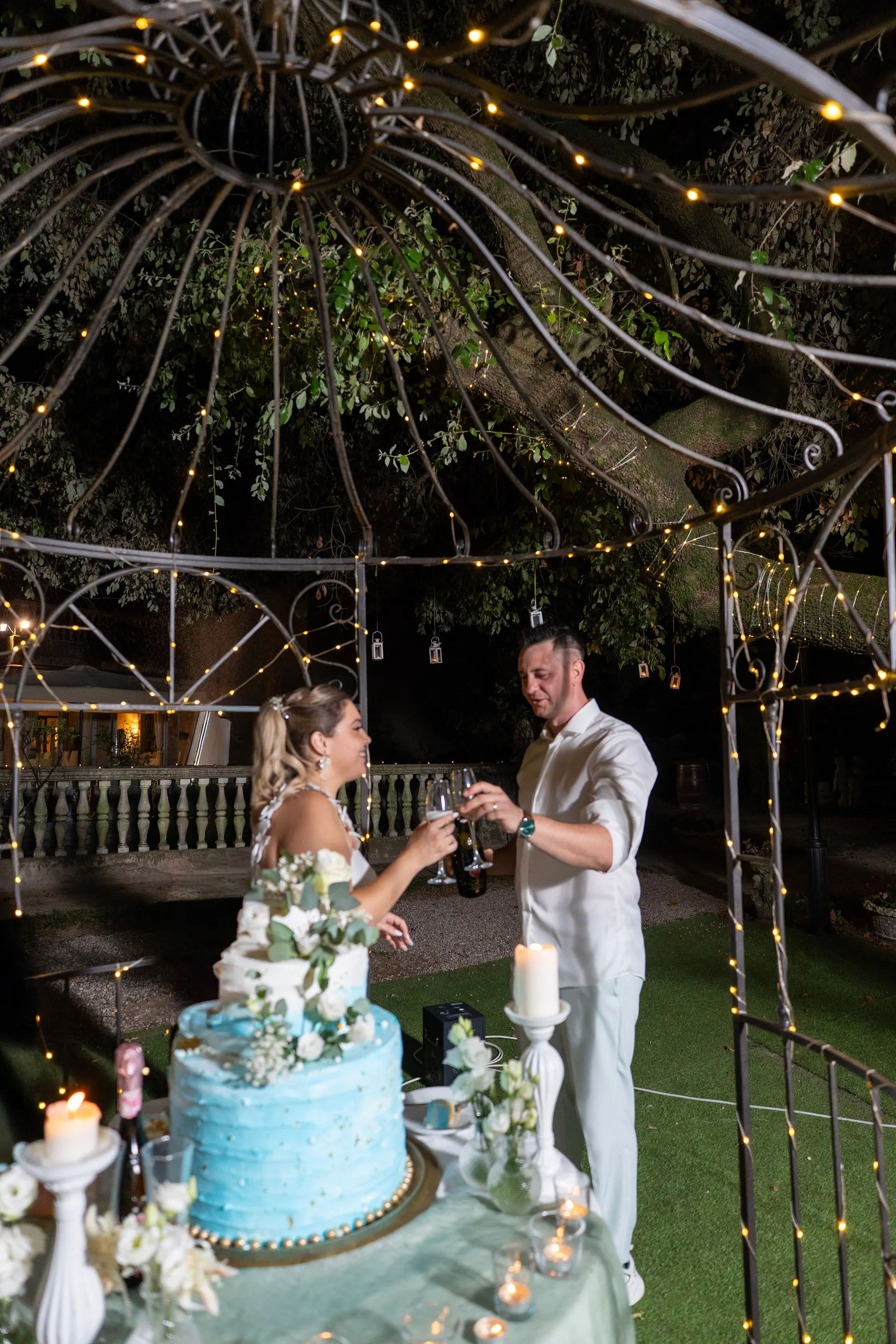 Brautpaar schneidet am Abend die Hochzeitstorte unter einem beleuchteten Pavillon an