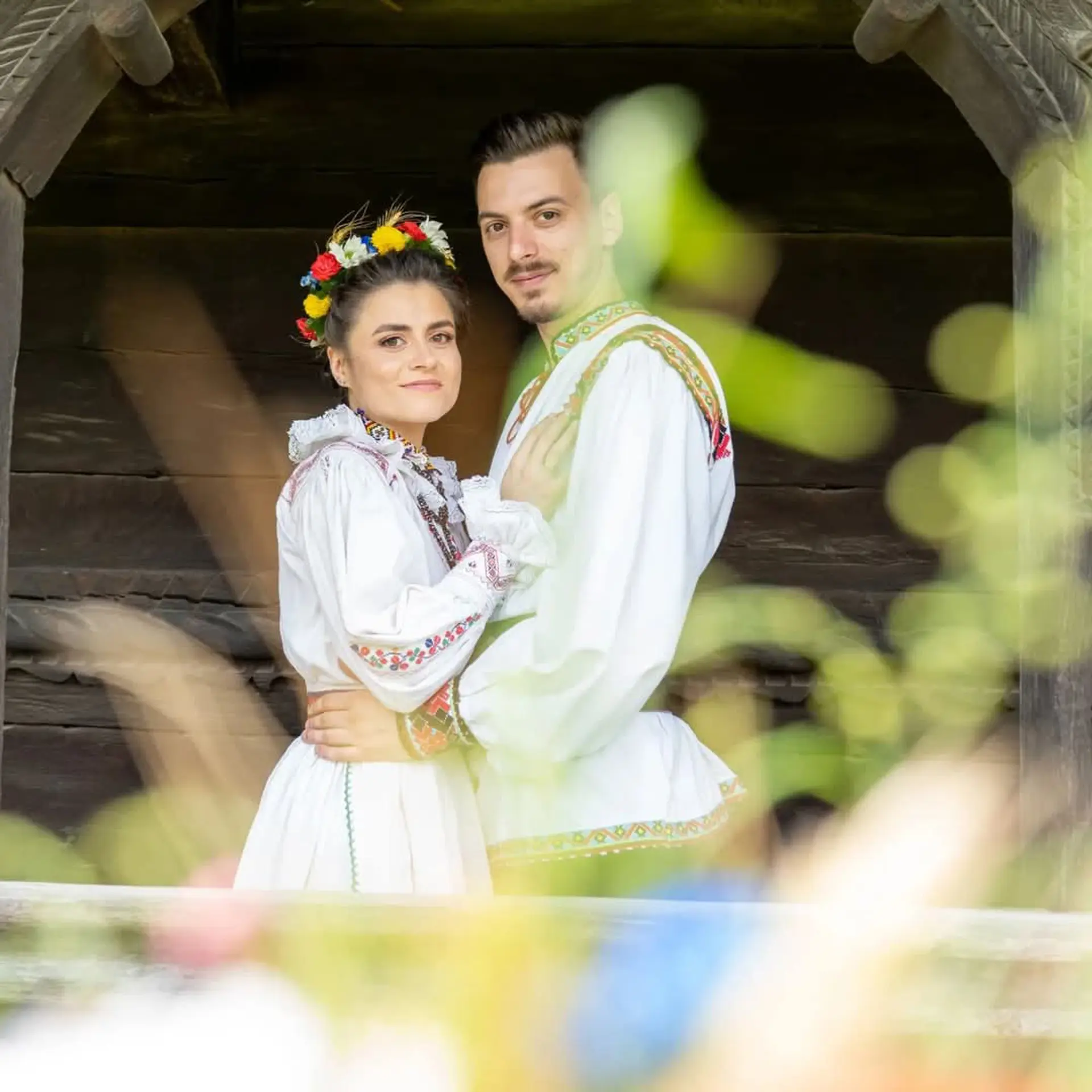 Paar in rumänischer Tracht vor einem alten Holzhaus