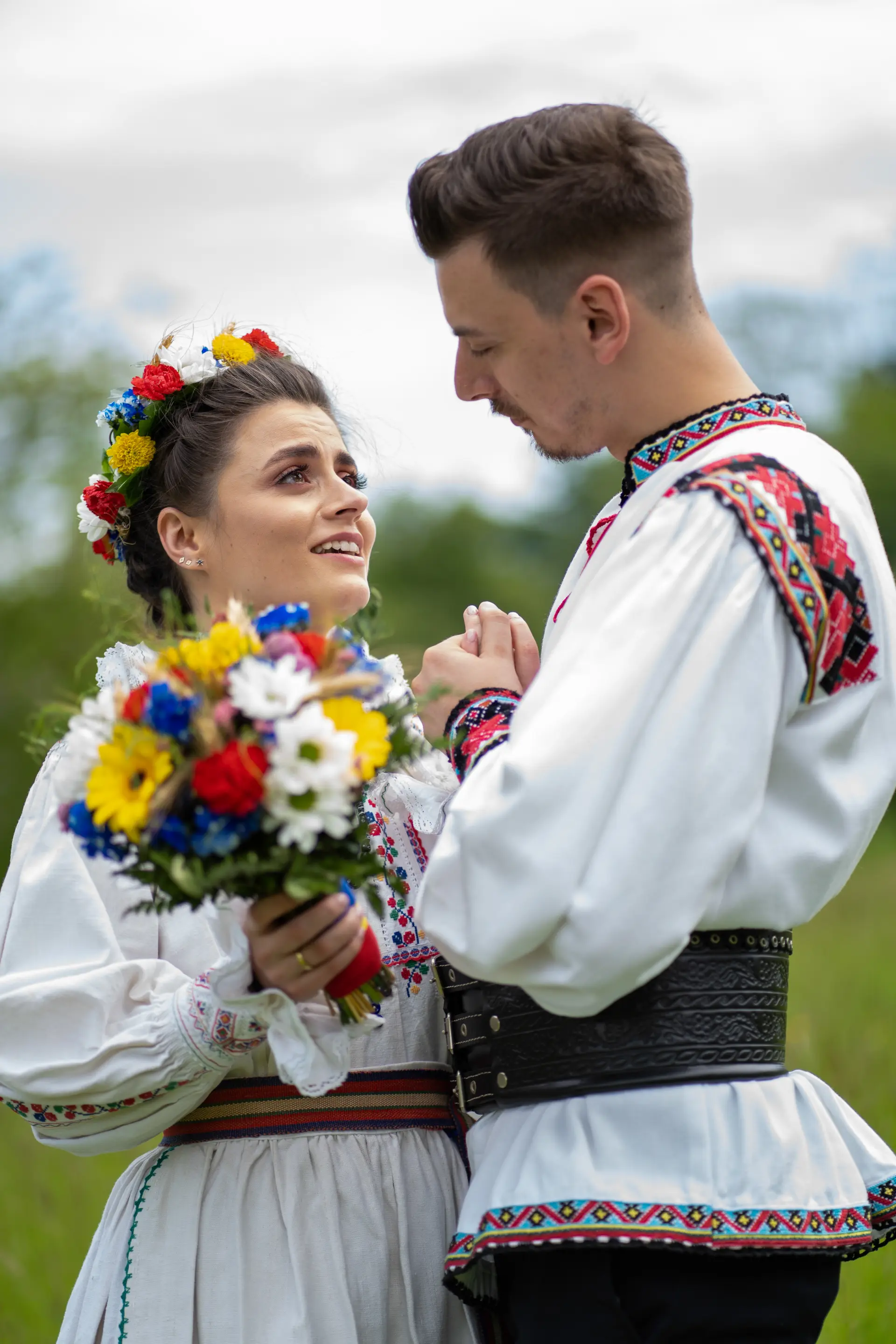 Paar in Tracht schaut sich an, sie hält einen bunten Blumenstrauß