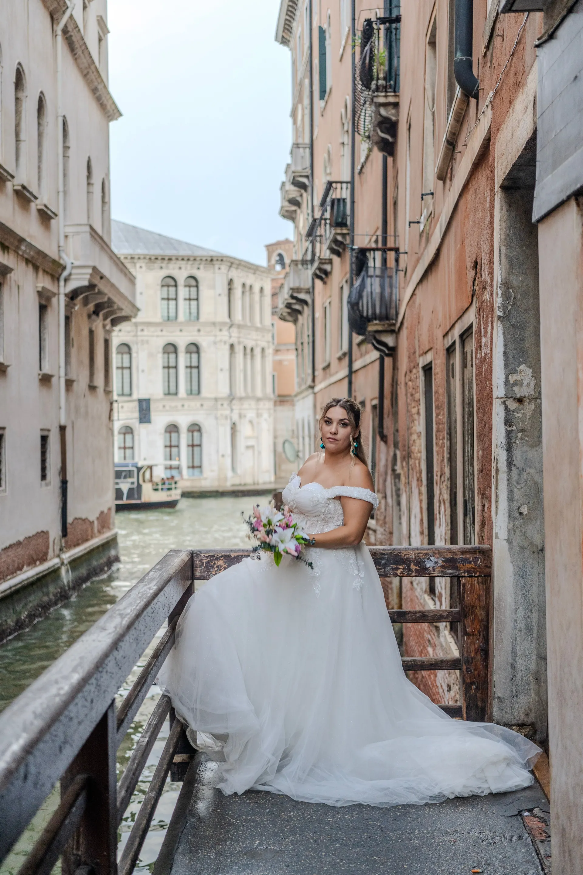 Braut sitzt auf einer kleinen Brücke an einem Kanal in Venedig
