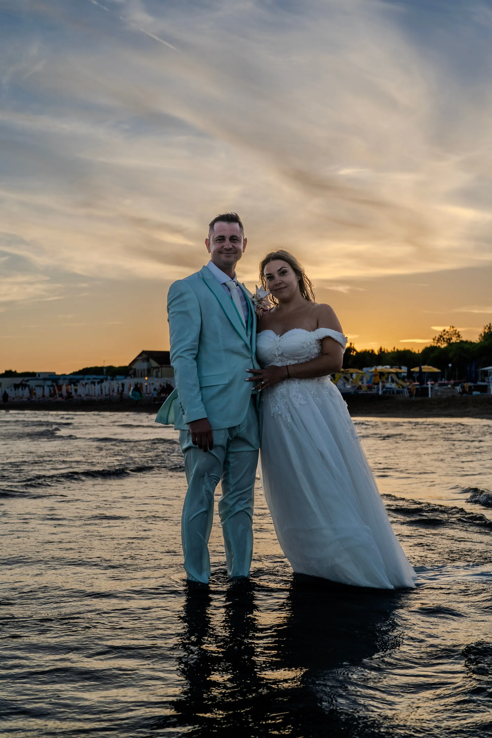 Brautpaar steht bei Sonnenuntergang im flachen Meer