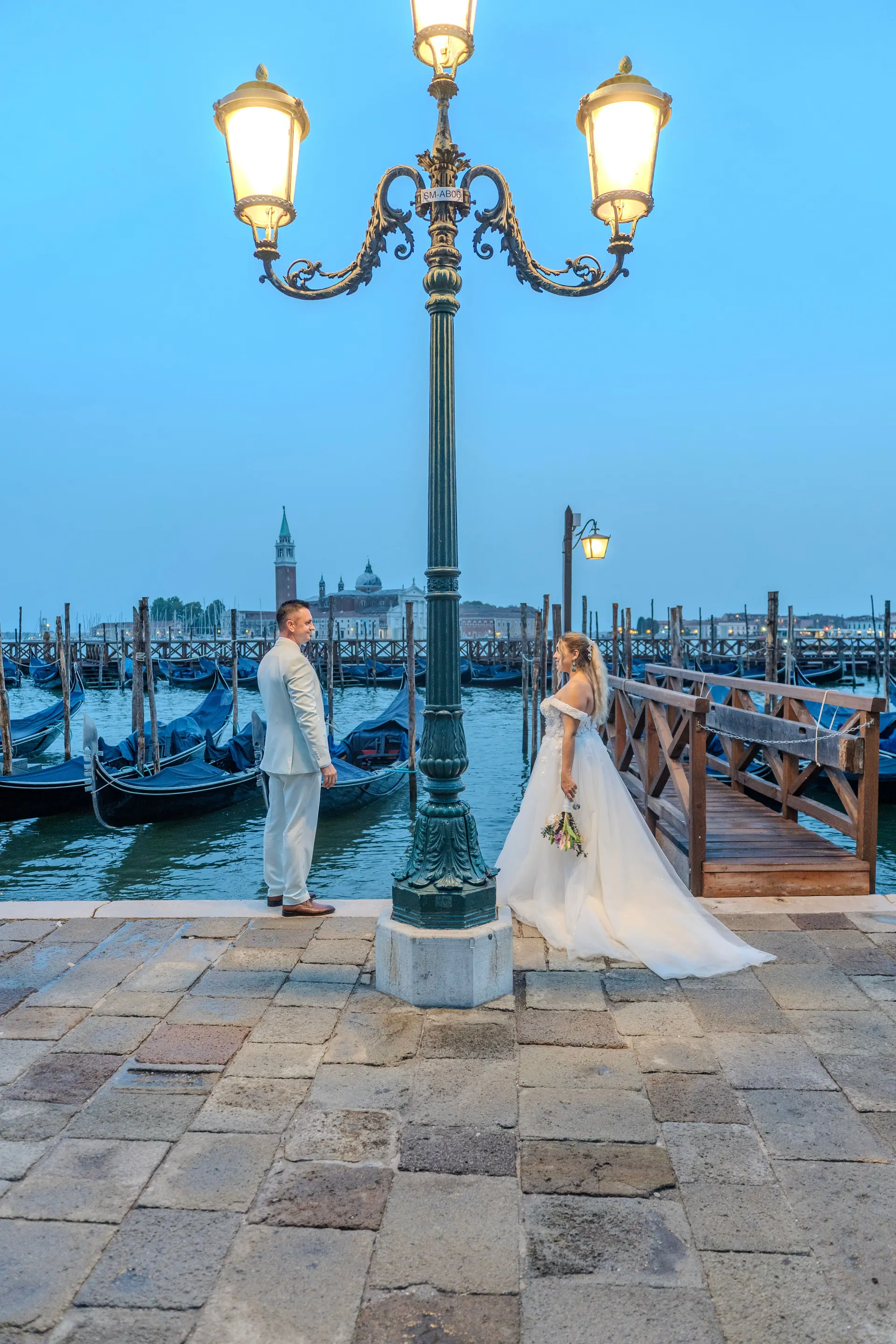 Brautpaar unter einer Laterne in Venedig, dahinter Gondeln und San Giorgio Maggiore