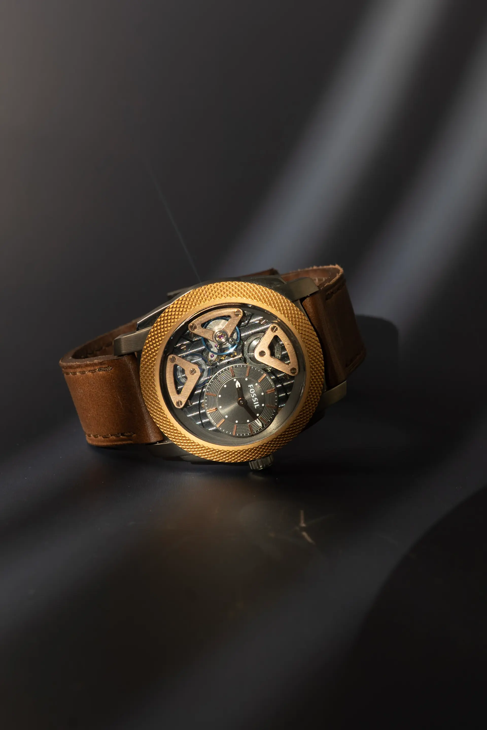 Armbanduhr mit Lederarmband vor dunklem Hintergrund mit Lichtstreifen, eigene Produktaufnahme